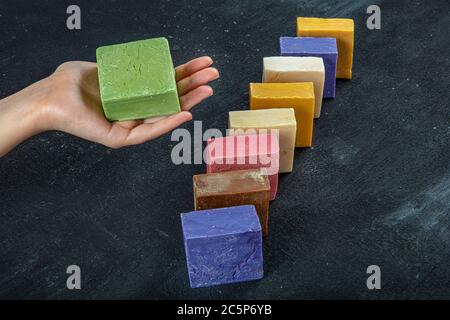 Femme tenant main savon naturel d'huile d'olive. Beaucoup de différents porte-savon faits main sur fond de bois noir Banque D'Images