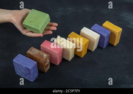 Femme tenant main savon naturel d'huile d'olive. Beaucoup de différents porte-savon faits main sur fond de bois noir Banque D'Images