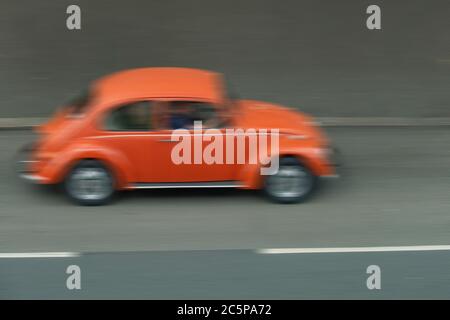 Une voiture Beetle orange floue roule à grande vitesse Banque D'Images