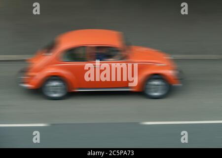 Une voiture Beetle orange floue roule à grande vitesse Banque D'Images