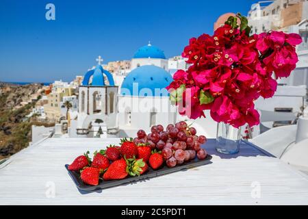 Fruits frais et fleurs sur une table en bois sur fond de l'île de Santorin Banque D'Images