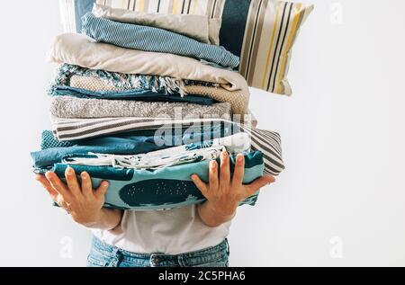 Femme portant la grande pile de linge bleu et beige dans ses mains. Image de concept de travail à domicile pour femme. Banque D'Images