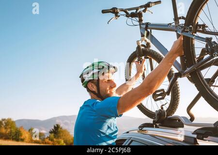 Homme motard de montagne prendre de son vélo devant le toit de voiture. Image de concept de sport actif Banque D'Images