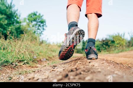 Trekking chaussure semelle gros plan image voyageur pieds dans des bottes de trekking sur la montagne sale chemin à l'été.vue arrière. Banque D'Images