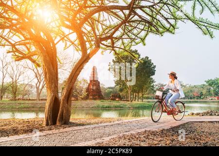 La femme voyageur a confecté des vêtements d'été légers et un chapeau ont fait une promenade à vélo tôt le matin dans le parc historique d'Ayutthaya, en Thaïlande Banque D'Images