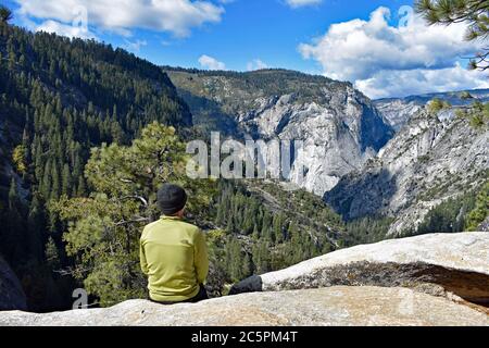 Un randonneur admirant la vue depuis le sommet des chutes du Nevada dans la vallée de Little Yosemite, en regardant vers Glacier point dans le parc national de Yosemite, Californie Banque D'Images