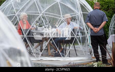 Le chef et propriétaire Josh Green vérifie les convives dans leurs gousses de repas en plein air qui ont été installées pour prendre des distances sociales au Barn Restaurant, à Terrington St John, Cambridgeshire, alors qu'il rouvre à nouveau suite à l'assouplissement des restrictions de confinement des coronavirus dans toute l'Angleterre. Banque D'Images