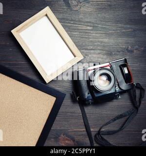 Appareil photo vintage et cadres photo vierges sur fond de table en bois. Pose à plat. Banque D'Images