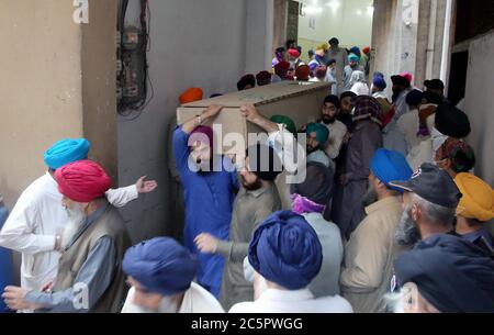 Les membres de la communauté sikh portent le cercueil de leurs proches, qui ont été tués vendredi après-midi dans un accident entre un autobus et un train près de Sheikhupura, lors d'une cérémonie funéraire tenue à Gurdwara Bhai Joga Singh à Peshawar, le samedi 4 juillet 2020. Une vingtaine de personnes, principalement des pèlerins sikhs, sont redoutées comme mortes dans un accident entre un bus et un train près de Sheikhupura vendredi après-midi. Le bus transportant les pèlerins a été frappé à un passage de chemin de fer sans pilote par le Shah Hussain Express à destination de Karachi. Banque D'Images