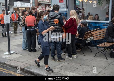 Table Service Super Saturday, Londres 4 juillet 2020. Les bars et pubs rouvrent avec restrictions en place, social distance, service de table, nombre limité de buveurs au bar. Le service de table de serveuse du bar Portobello Road Gin. 2020 UK HOMER SYKES Banque D'Images