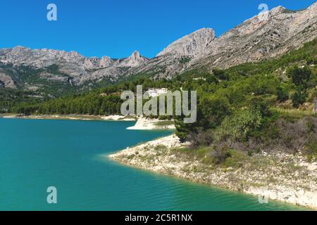 Lac de réserevoir de barrage de couleur turquoise entouré de montagnes rocheuses et de forêt verte à Guadalest, Costa Blanca, Espagne Banque D'Images