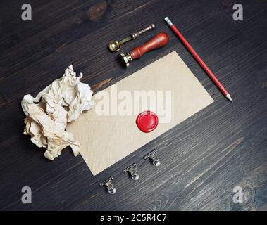 Papeterie postale vintage. Enveloppe vierge, cire d'étanchéité, tampon, cuillère, crayon et papier froissé sur fond de table en bois. Modèle performant. Banque D'Images