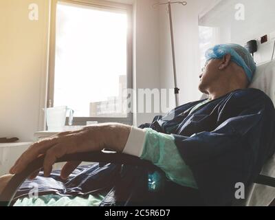 Couché sur la chaise médicale homme senior à l'intérieur de l'hôpital moderne en France se reposant après infection virus coronavirus - grande fenêtre d'espoir avec des reflets de soleil Banque D'Images