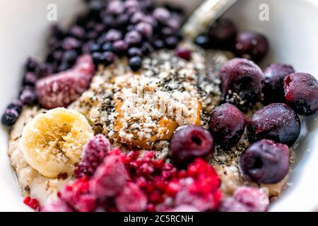 Macro gros plan texture de la farine d'avoine bouillie de porc avec beurre d'arachide, baies congelées framboises bleuets et cerises avec des graines de banane et de chia Banque D'Images