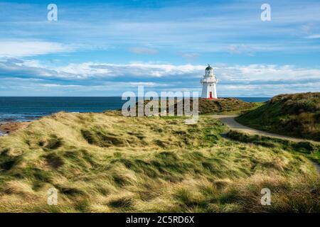 Le phare historique de Waipapa point entouré de dunes de sable herbeuses par une journée ensoleillée et nuageux sur la côte de Dunedin Banque D'Images