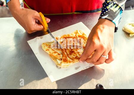 Mains du vendeur de rue cuisant du pain sucré de style thaïlandais sur une poêle en acier ou une grande poêle à frire plate. Dégustez la cuisine de la rue en Thaïlande. Banque D'Images