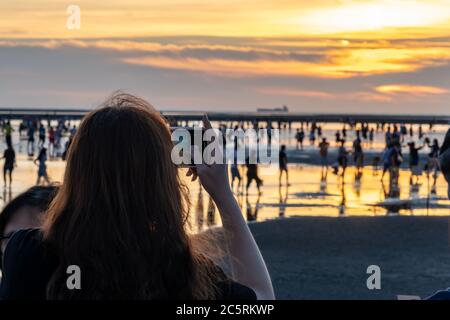 Des gens bondés jouant l'eau dans les zones humides de Gaomei pendant l'heure du coucher du soleil. District de Qingshui, Taichung City, Taïwan Banque D'Images