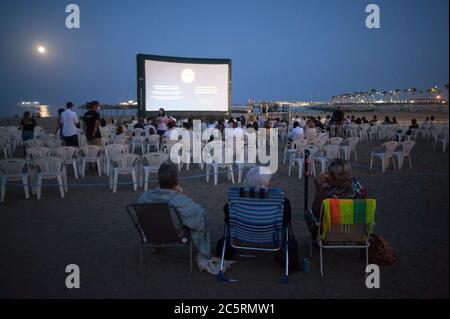 Malaga, Espagne. 04e juillet 2020. On voit des femmes s'asseoir sur des chaises de plage pendant qu'elles attendent un film à la plage de la Malagueta, au milieu des épidémies de coronavirus (COVID-19). Pendant la saison estivale, l'événement « Open Cinema » accueille des projections de films gratuites du 2 juillet au 20 août dans différents lieux de plein air comme les plages, les parcs ou les zones de quartier, tandis que les gens peuvent profiter de films gratuits à cette occasion, ces endroits doivent adapter les mesures de sécurité et de santé pour prévenir la propagation de la pandémie du coronavirus. Crédit : SOPA Images Limited/Alamy Live News Banque D'Images