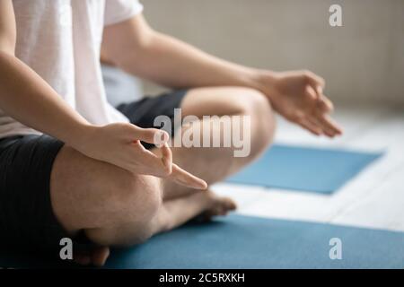 Gros plan jeune homme assis en position lotus avec le geste de mudra, Banque D'Images