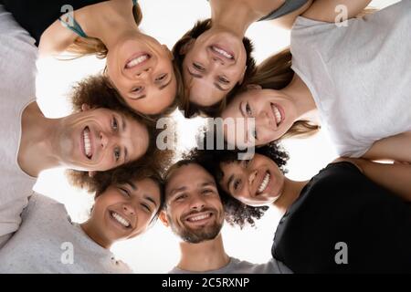 Souriant, les gens de race mixte touchent les têtes en cercle. Banque D'Images