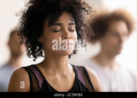 Jeune femme afro-américaine paisible bénéficiant d'une profonde méditation. Banque D'Images