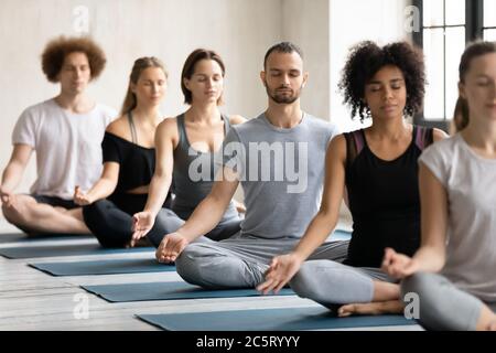 Les jeunes sont des personnes multiraciales qui méditent en pamasana. Banque D'Images