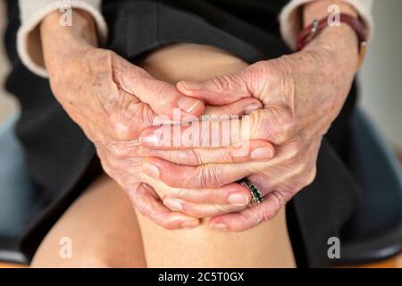 Femme âgée assise avec les mains jointes Banque D'Images