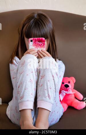 Une jeune fille de huit ans jouant sur un smartphone Banque D'Images