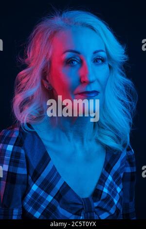Portrait de la vieille femme dans des lumières vives colorées. Bleu et rouge Banque D'Images