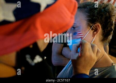 Un homme israélien vêtu de la tenue de l'oncle Sam peint le drapeau américain sur le visage d'une femme lors de la célébration du jour de l'indépendance des États-Unis le 4 juillet à Jérusalem Israël. Banque D'Images