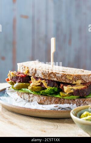 Salez le sandwich au bœuf avec du concombre mariné et de la sauce tartare de moutarde Banque D'Images