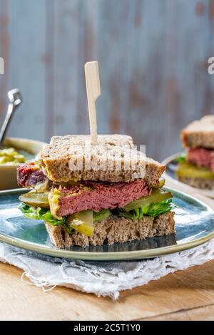 Salez le sandwich au bœuf avec du concombre mariné et de la sauce tartare de moutarde Banque D'Images