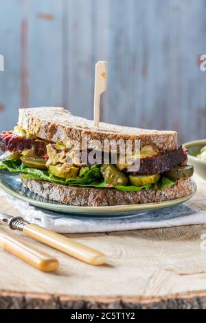 Salez le sandwich au bœuf avec du concombre mariné et de la sauce tartare de moutarde Banque D'Images