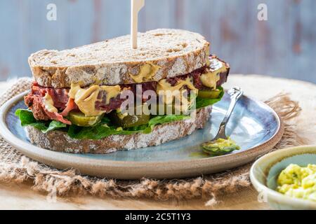 Salez le sandwich au bœuf avec du concombre mariné et de la sauce tartare de moutarde Banque D'Images