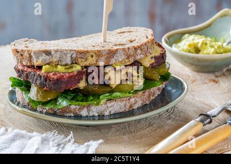 Salez le sandwich au bœuf avec du concombre mariné et de la sauce tartare de moutarde Banque D'Images