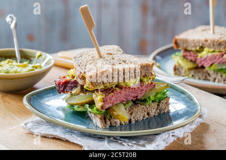 Salez le sandwich au bœuf avec du concombre mariné et de la sauce tartare de moutarde Banque D'Images