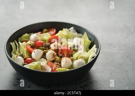 Salade avec avocat, tomates et mozzarella dans un bol noir Banque D'Images