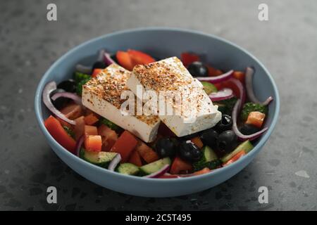 Salade grecque traditionnelle dans un bol bleu sur fond de béton Banque D'Images