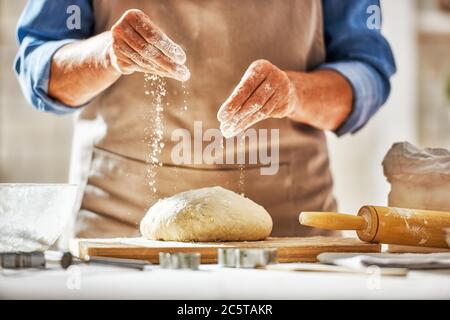 Vue rapprochée du boulanger en cours. Pain maison. Mains préparant la pâte sur une table en bois. Banque D'Images