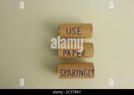 Écriture de l'écriture de l'enseigne avec message utiliser le papier écrit avec parcimonie sur trois rouleaux de papier toilette vides sur une surface en bois, vue à grand angle, concept de changement climatique Banque D'Images