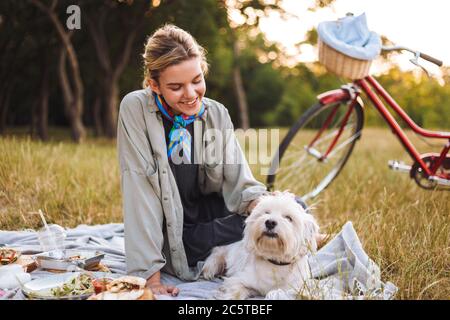 Jolie fille souriante qui a fait un petit chien mignon qui a dépensé le TI Banque D'Images