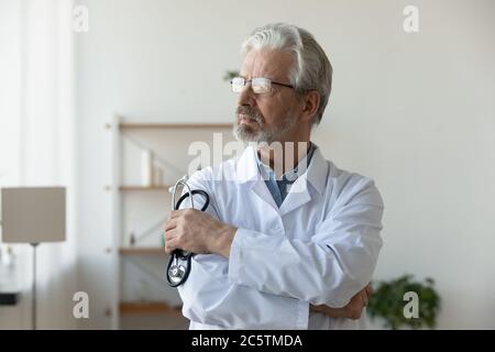 Pensive mature homme médecin regarder dans la pensée à distance Banque D'Images