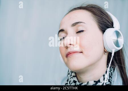 Une jeune fille de race blanche sourit et écoute de la musique avec les yeux fermés Banque D'Images