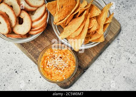 Mélange de chips, d'en-cas et de craquelins sur un support en bois. Aliments malsains, encas à la bière, repas préparés. Gros plan Banque D'Images