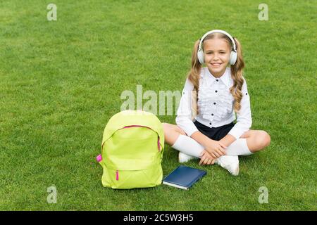 livre pour les petites filles. littérature pour les enfants. développement de l'enfance. travail avec un carnet. retour à l'école. étude des enfants dans le parc. détente sur l'herbe verte avec le livre. écoute de la musique en ligne. Banque D'Images