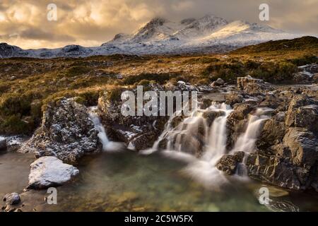 Des nuages spectaculaires sur l'île de Skye avec la chaîne de montagnes Cuillin couverte de neige, pris d'une chute d'eau près du pont Sligachan. Banque D'Images