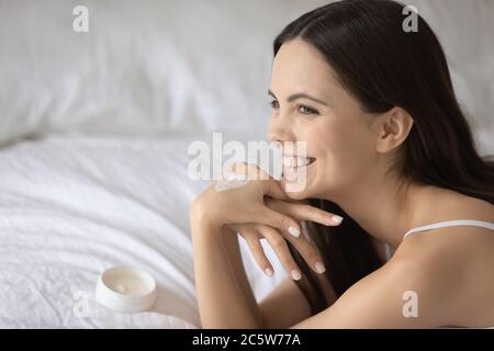 Jeune femme souriante avec crème hydratante en forme de coeur à portée de main Banque D'Images