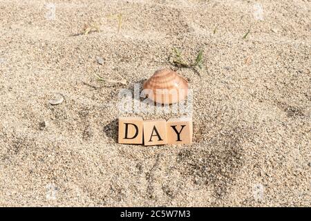 Mot de jour en cubes de bois. Gros plan sur la plage de sable. Banque D'Images