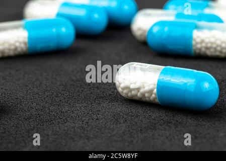 Capsules de gélatine bleue avec granules blancs à l'intérieur, isolées sur fond noir, macro-shot. Banque D'Images