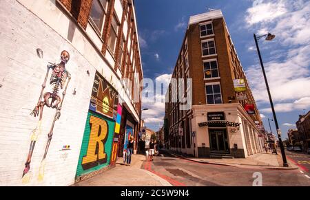 Londres, Angleterre, Royaume-Uni - 4 juillet 2010 : des piétons se promegent devant les œuvres d'art de rue sur les bâtiments de Rivington Street à Shoreditch, est de Londres. Banque D'Images